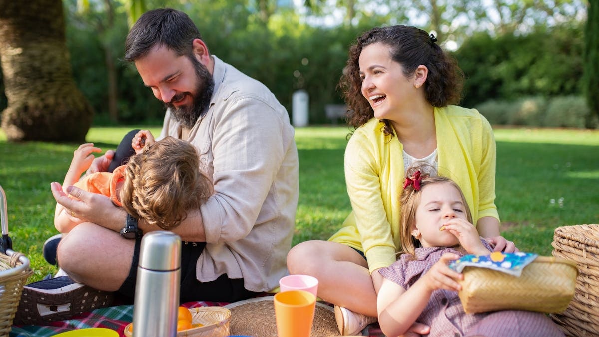 Happy family having a picnic on a sunny day in a park, enjoying togetherness and relaxation.